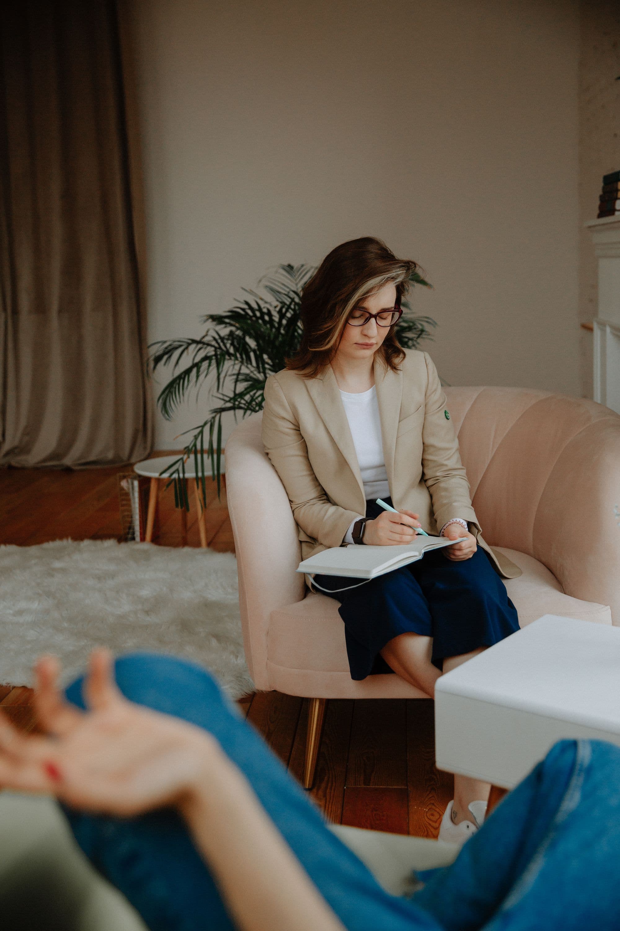 A psychologist sits in an armchair taking notes.