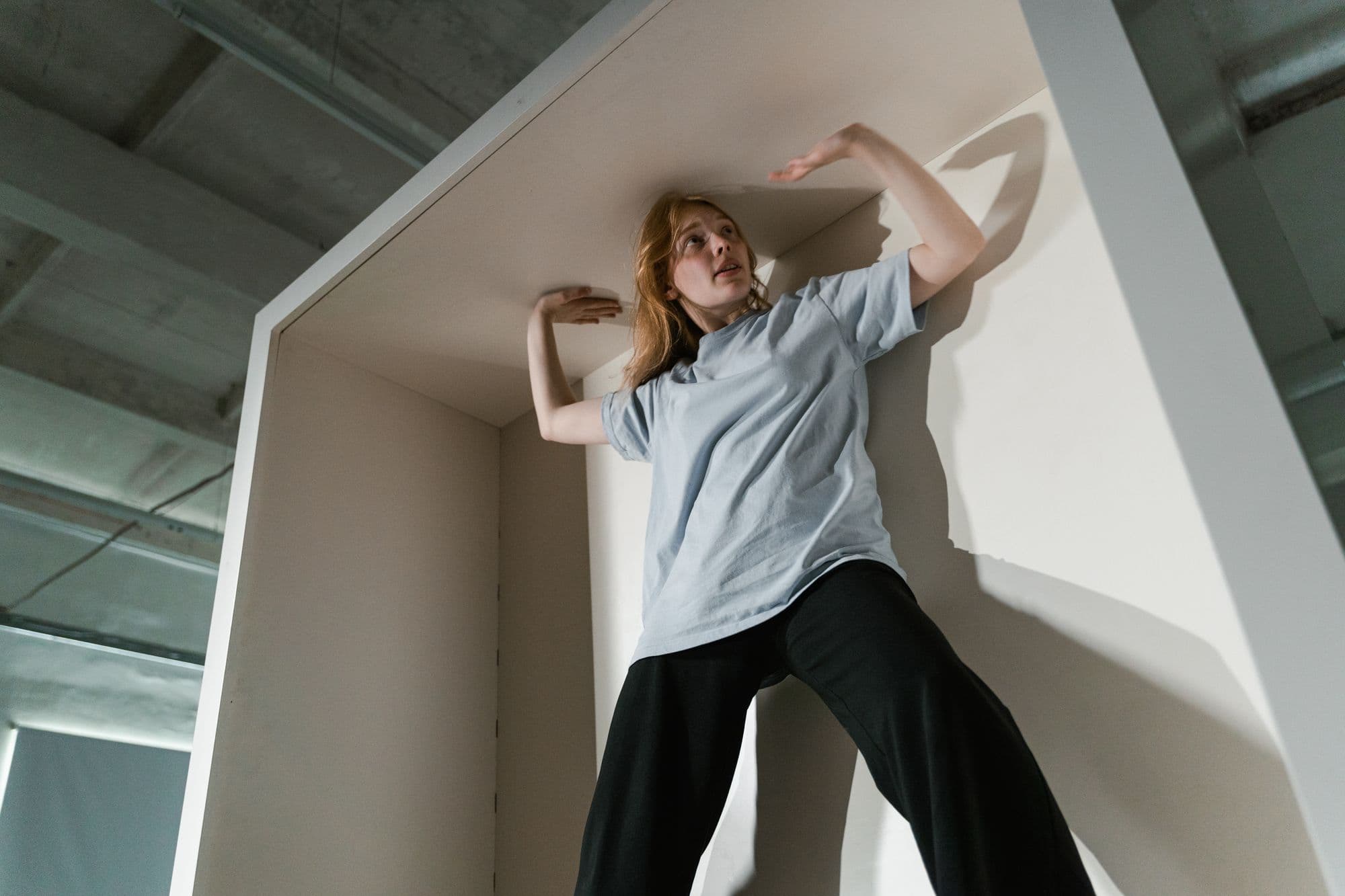 A woman presses against the walls of a cramped box, as if there were no room for her.