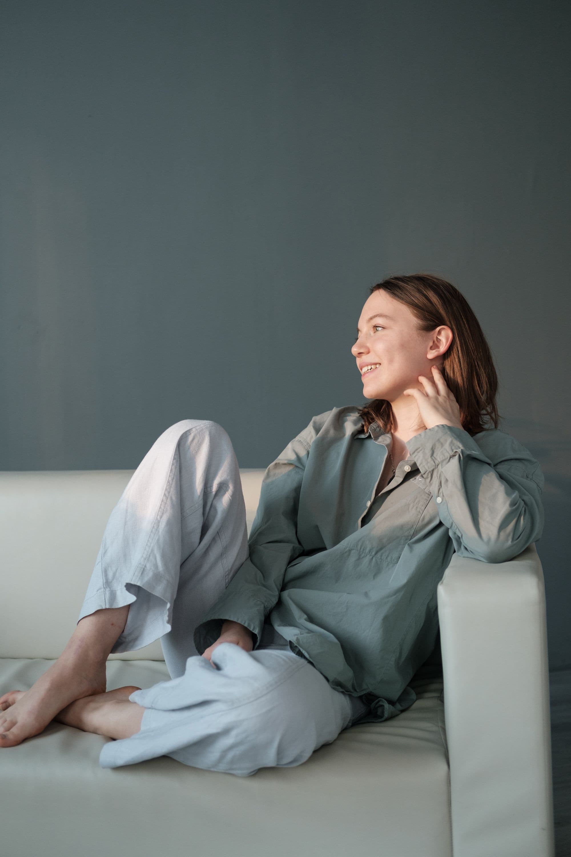 A relaxed, smiling woman sits on the couch.